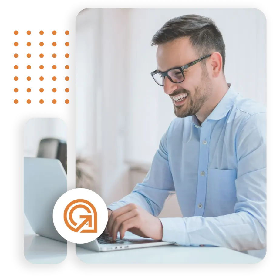 Man smiling while working on a laptop in a modern office setting